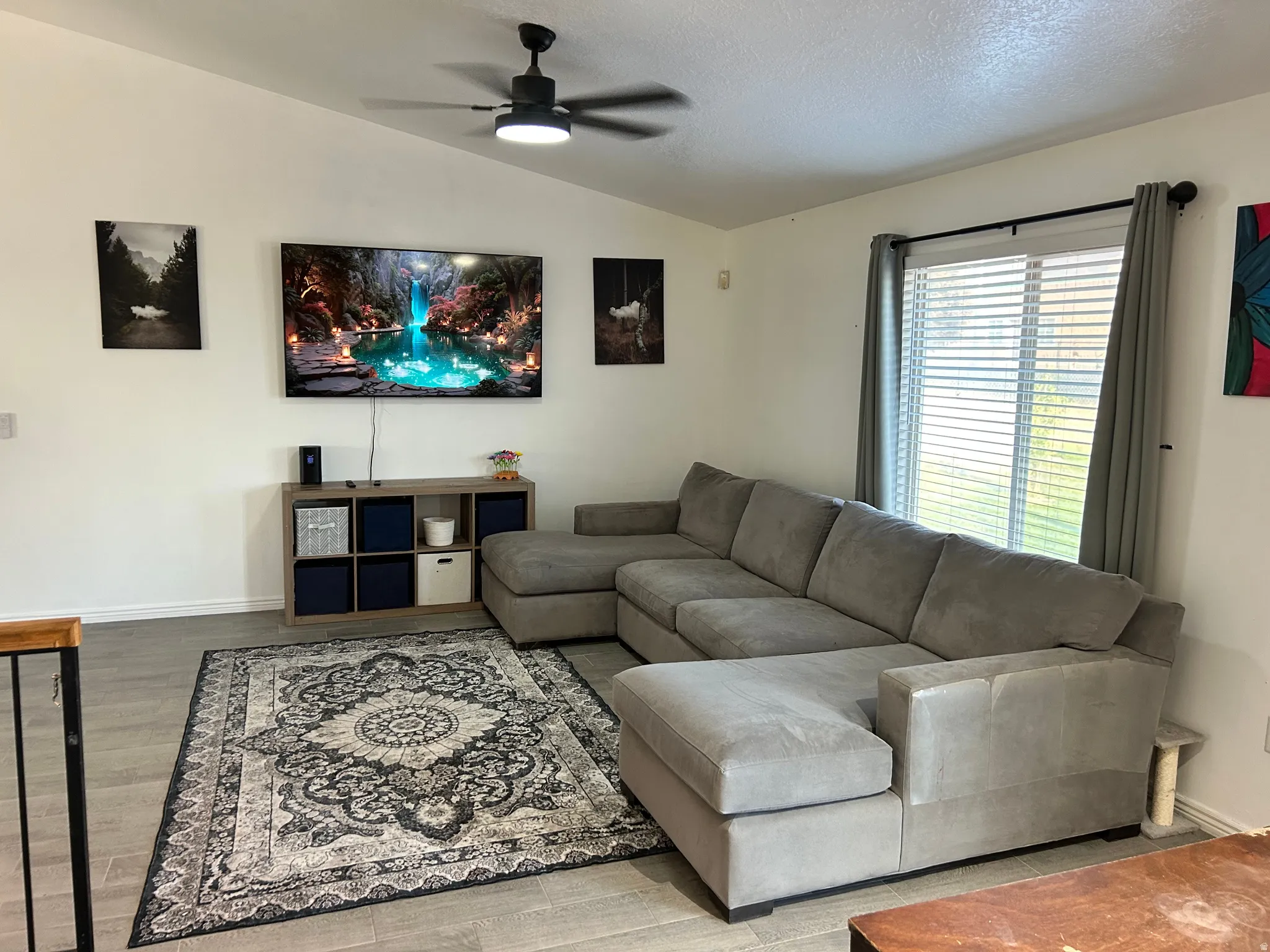 Vaulted ceilings with a ceiling fan, wall-mounted television, and wood-finish flooring