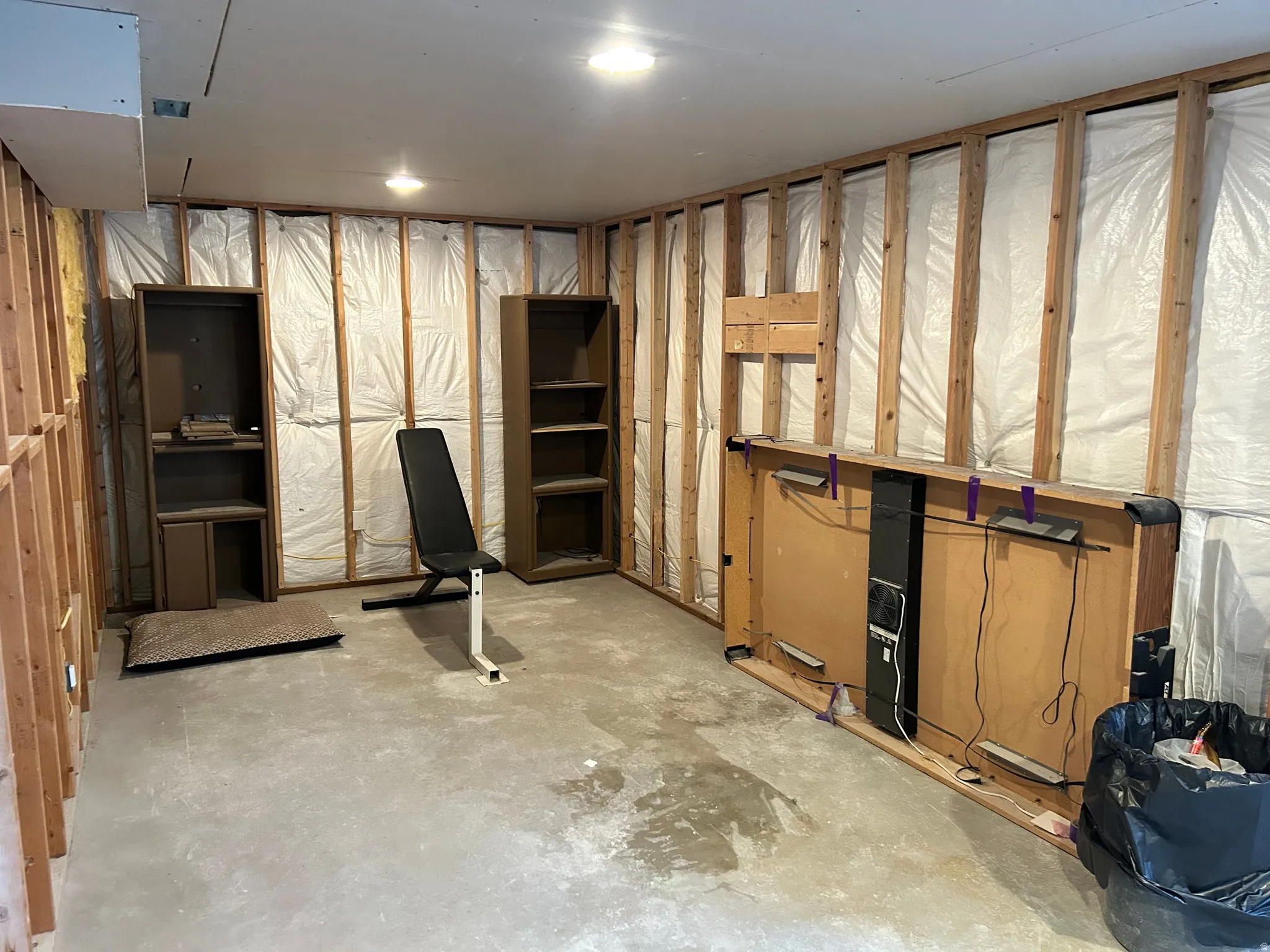 Unfinished basement space with exposed wood framing, concrete flooring, and ceiling-mounted lighting