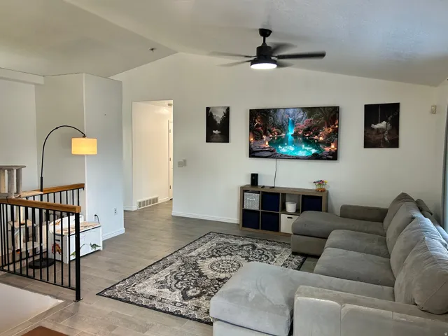 Vaulted ceilings, a contemporary ceiling fan with integrated lighting, and tile flooring create an open atmosphere