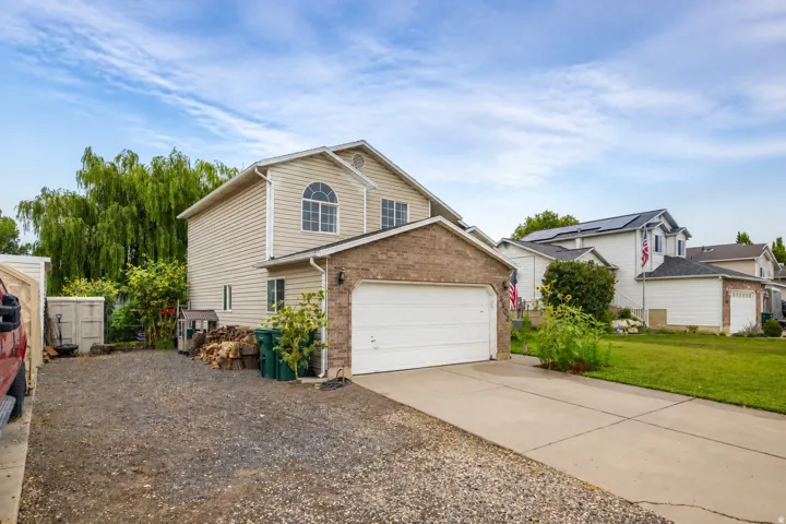 Two-story property featuring a two-car garage with a white door, light-colored siding, and brick-look accents