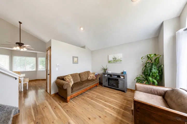 Vaulted ceiling, recessed lighting, wood-finish flooring, ceiling fan, and bay window