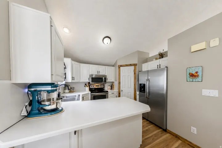 White cabinetry, stainless steel appliances, wood-finish flooring, white countertops, and recessed lighting