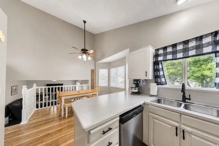 Kitchen featuring white cabinetry, stainless steel dishwasher, dual basin sink, and a black faucet