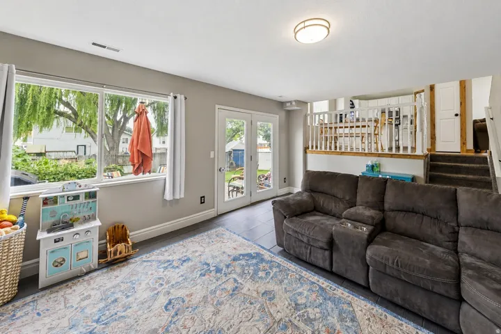 Recessed lighting, large windows, French doors, dark tile flooring, and a white balustrade with wood accents