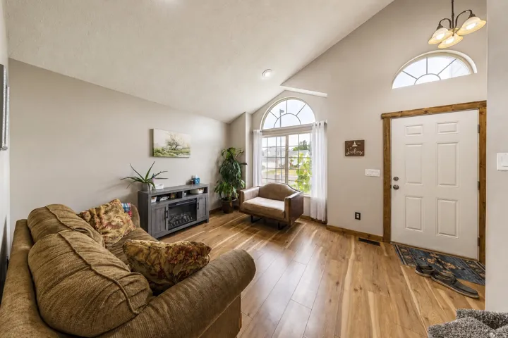 Vaulted ceiling, arched transom windows, wood-finish flooring, built-in electric fireplace, paneled entry door