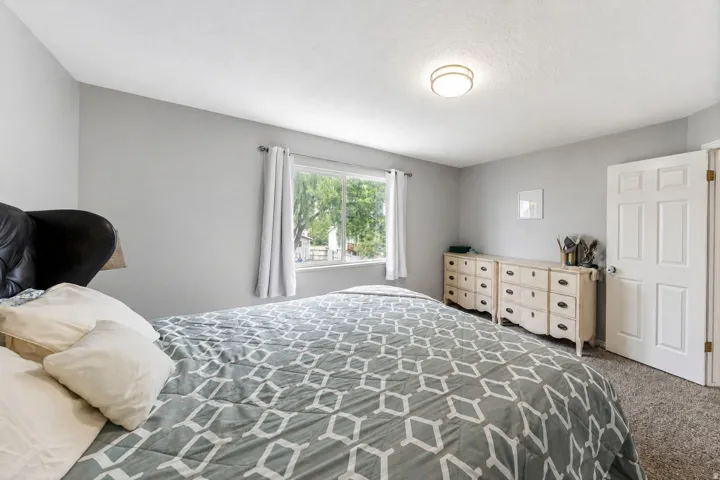 Light-colored walls, window with natural light, textured carpeting, overhead flush mount lighting, and a paneled door