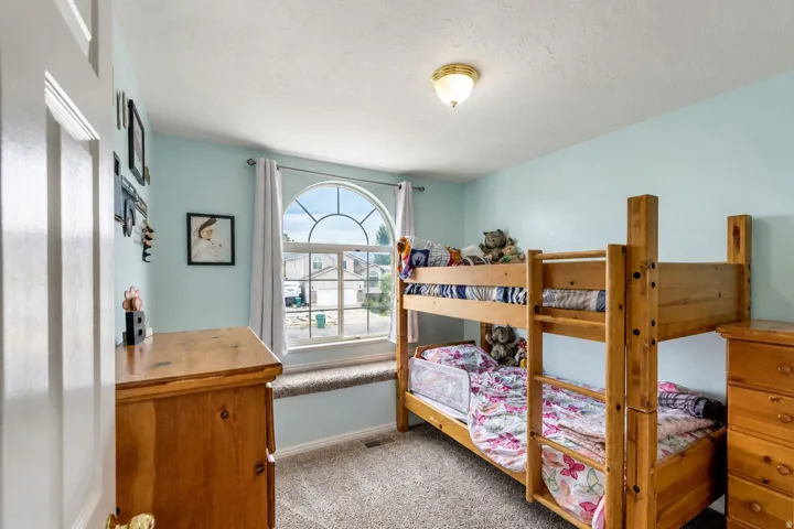 Arched window with decorative grilles, wall-to-wall carpeting, and a flush mount light fixture