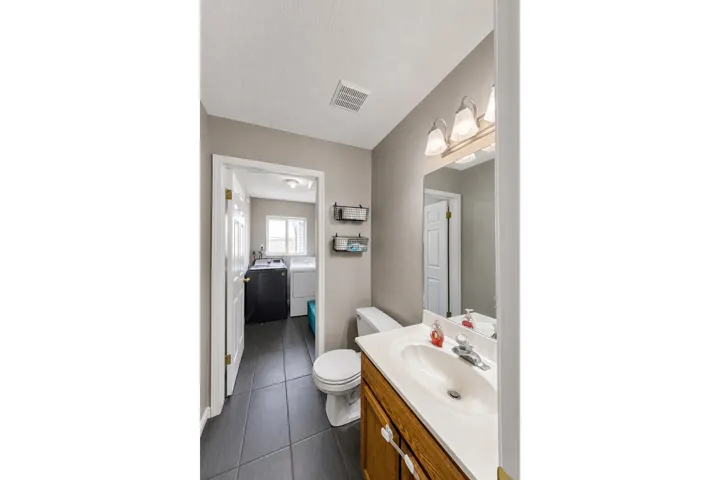 Bathroom with a wood-finish vanity, integrated sink, and wall-mounted mirror