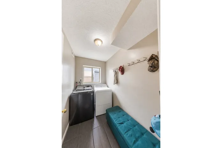 Laundry area featuring tile flooring, a window, and a wall-mounted coat rack