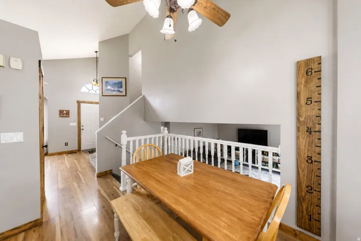 Open-concept design featuring wood-finish flooring, a two-story entryway, and a ceiling fan with integrated lighting