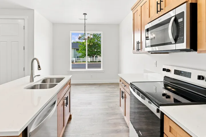 Kitchen featuring wood-finish cabinetry, stainless steel appliances, white countertops, and wood-finish flooring