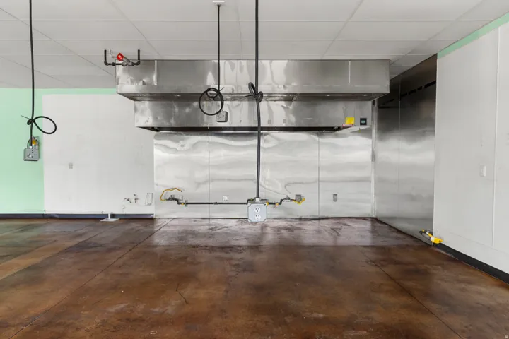 Stainless steel commercial-grade exhaust hood system with integrated fire suppression, stainless steel wall paneling, and a drop ceiling
