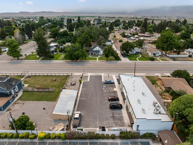 Expansive paved parking area, commercial building with a metal roof, and adjacent green space