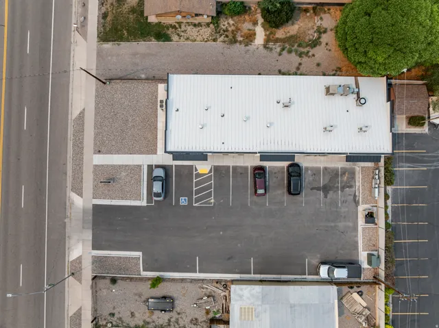 Building with a white metal roof, multiple rooftop units, and a paved parking lot with marked spaces