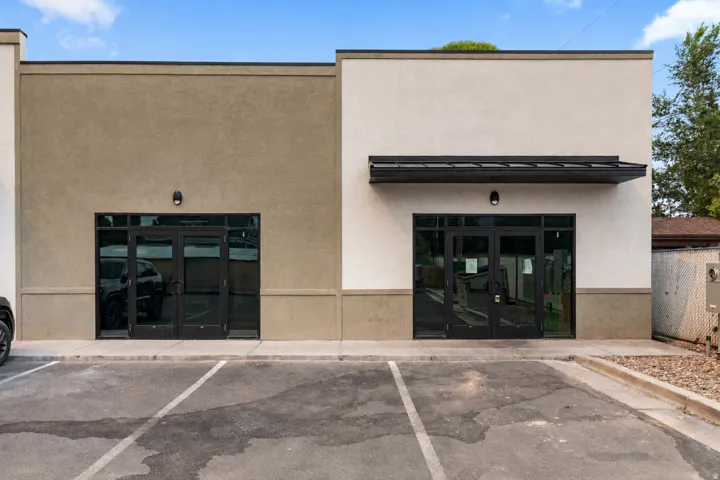 Stucco exterior with a modern awning, two separate entrances, and a paved parking area