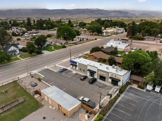 Commercial building featuring multiple storefronts, ample paved parking, and a prominent roadside location