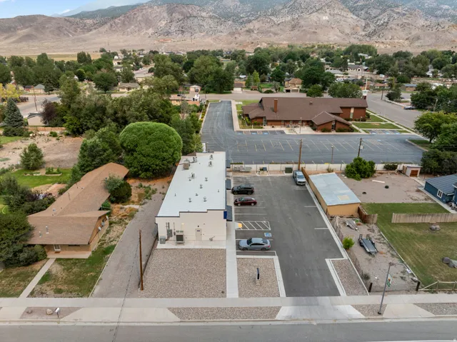 Flat roof building with an asphalt parking area, gravel landscaping, and a mountain backdrop