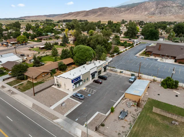 Commercial building with multiple storefronts, ample paved parking, and a gravel lot