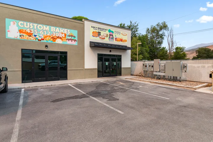 Commercial building with a paved parking lot, multiple storefront entrances, and exterior signage