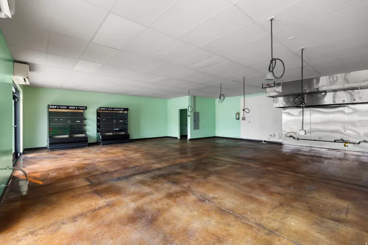 Spacious interior with an exposed ceiling grid, concrete flooring, and an integrated commercial-grade exhaust system