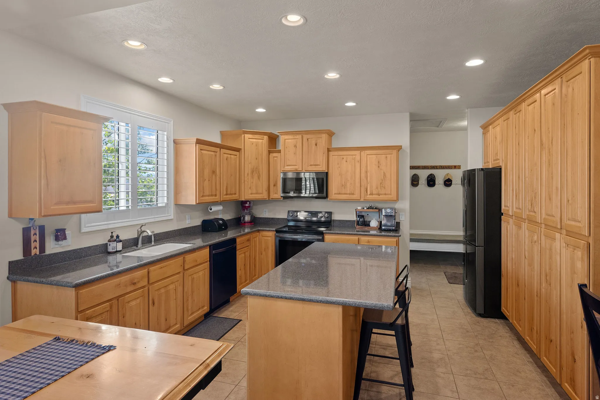 Kitchen featuring recessed lighting, a built-in microwave, wood cabinetry, a center island with countertop seating, and tile flooring
