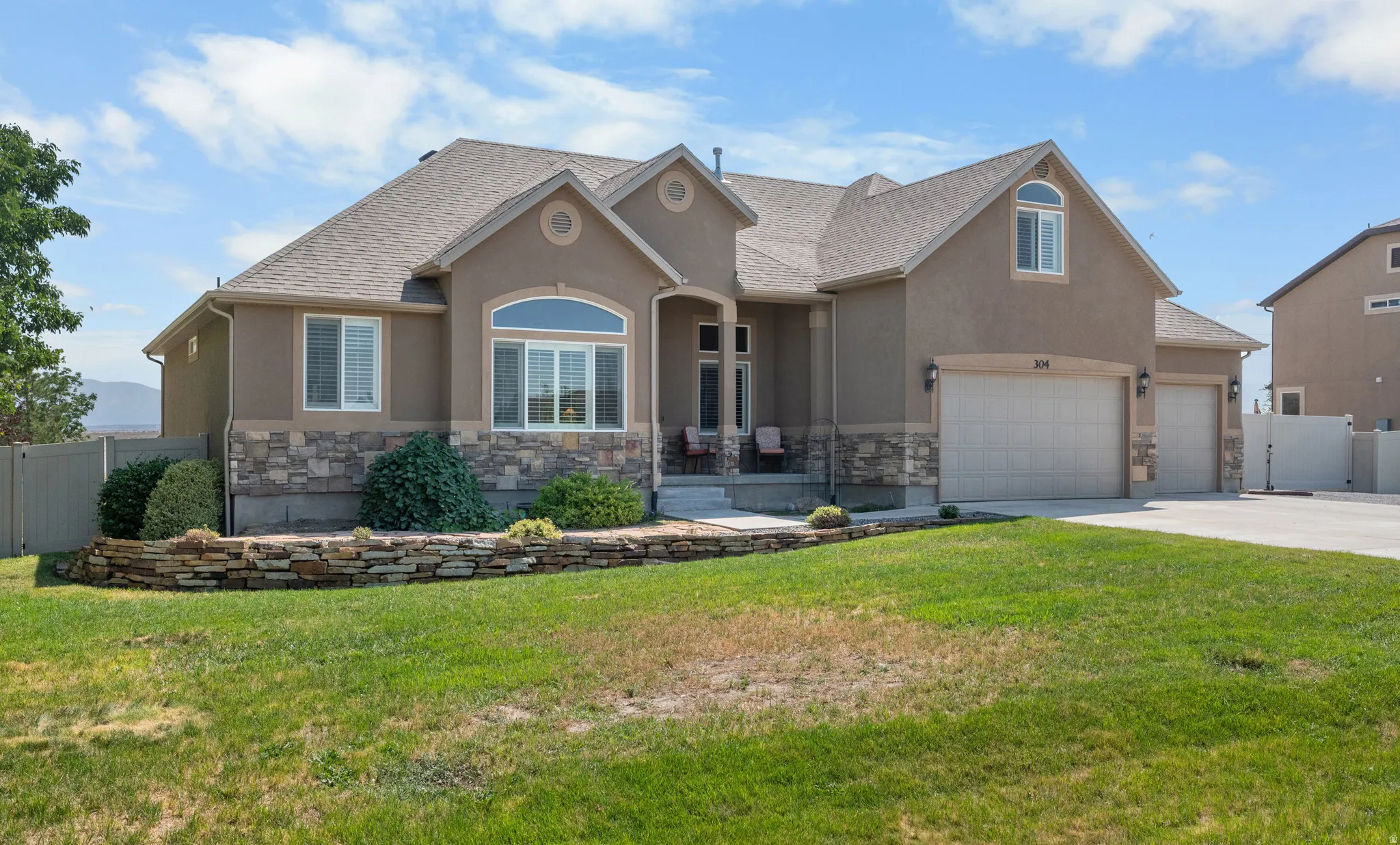 Stucco exterior with stone accenting, multi-paned windows, a two-car garage, and a concrete driveway