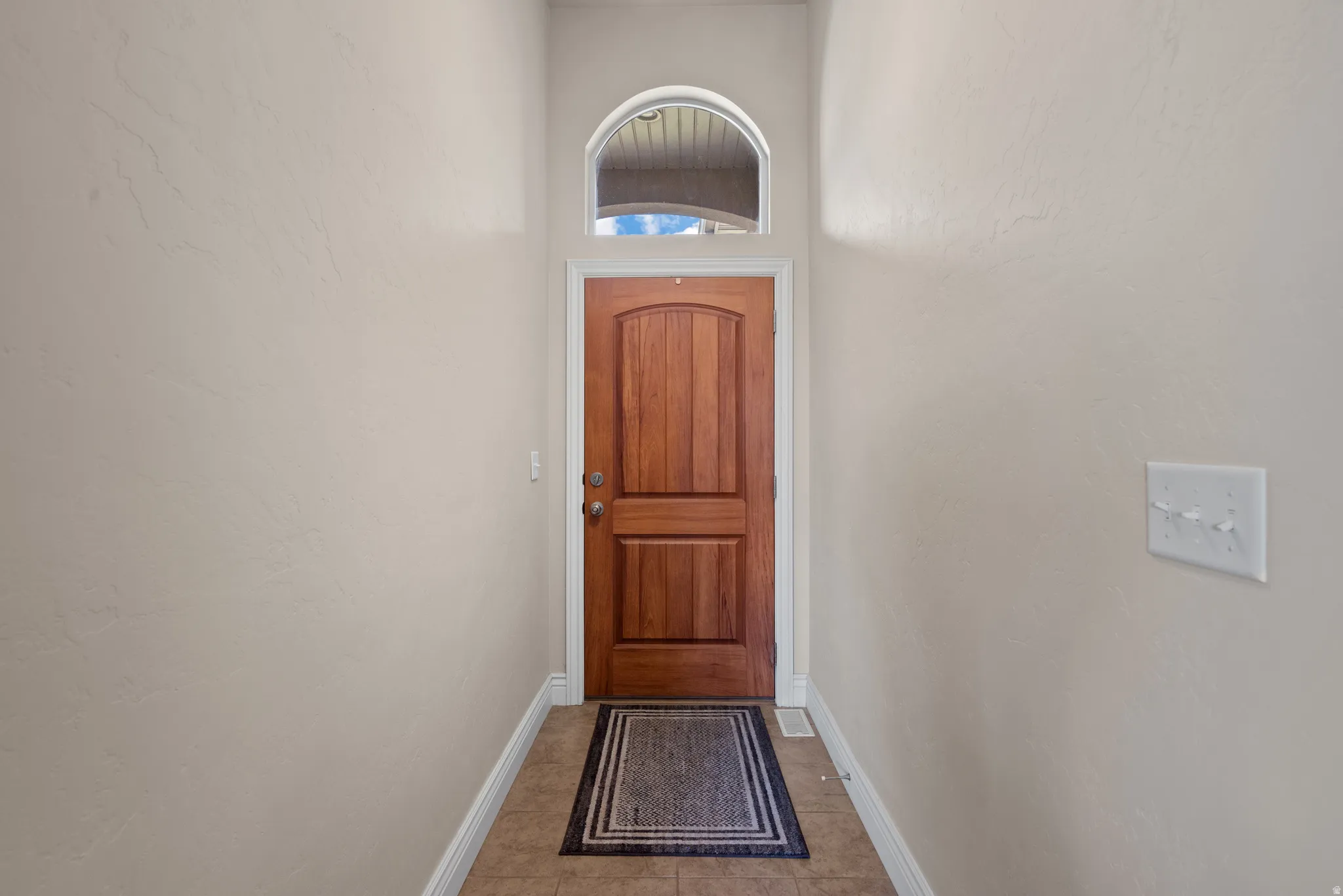 Wood-panel entry door with an arched transom window