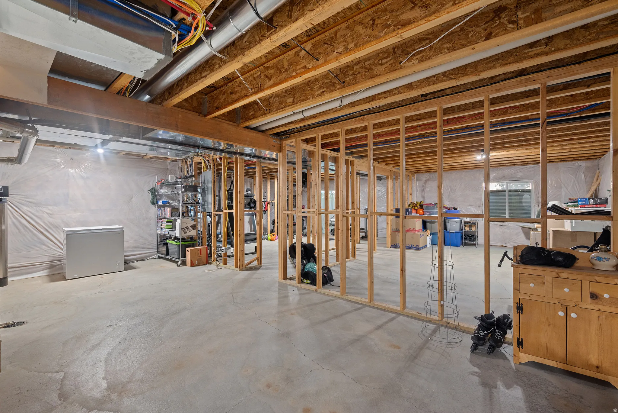 Unfinished basement with concrete flooring, exposed wooden joists, and framed partition walls