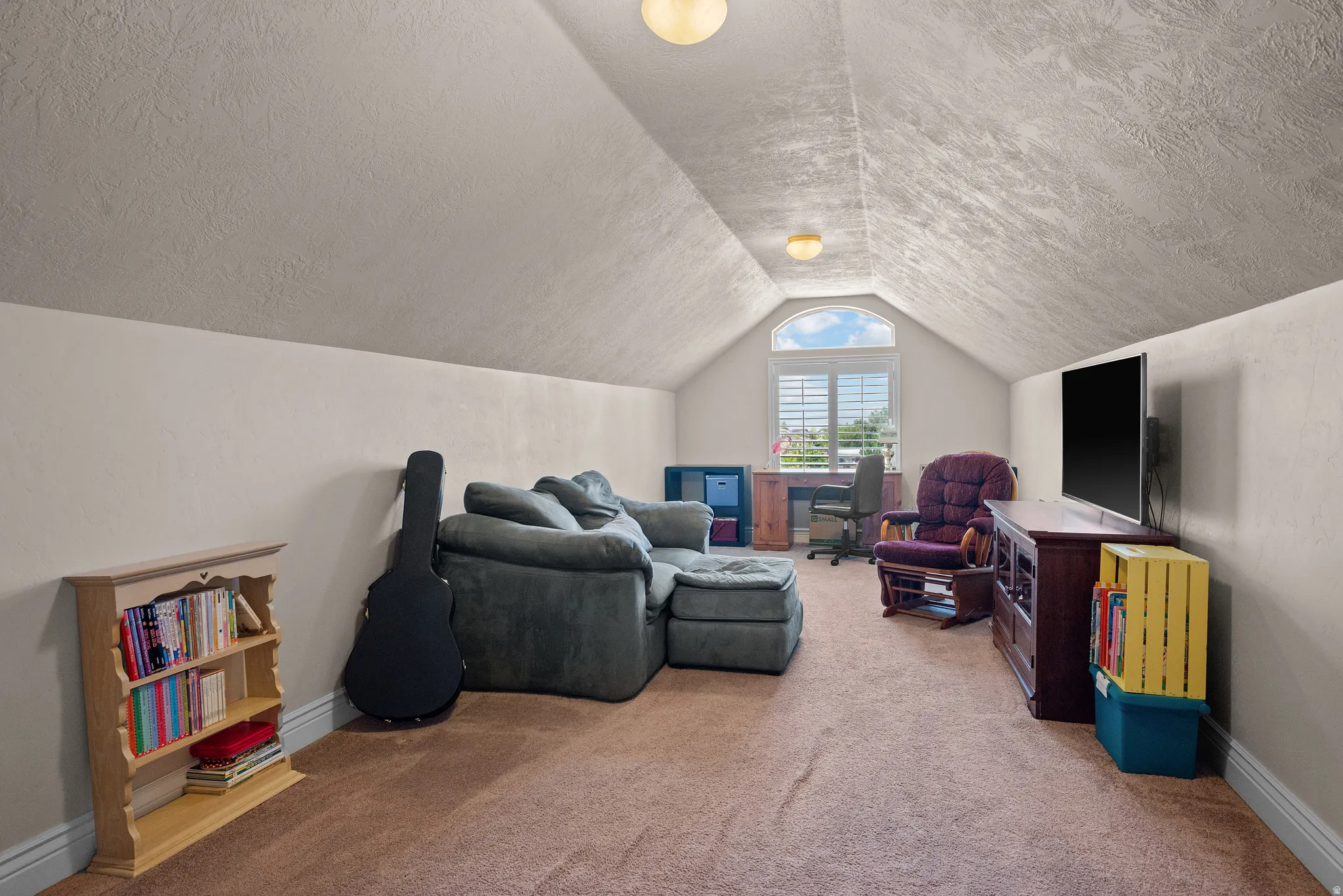 Vaulted ceiling with textured finish, arched window with plantation shutters, recessed lighting, and carpeting