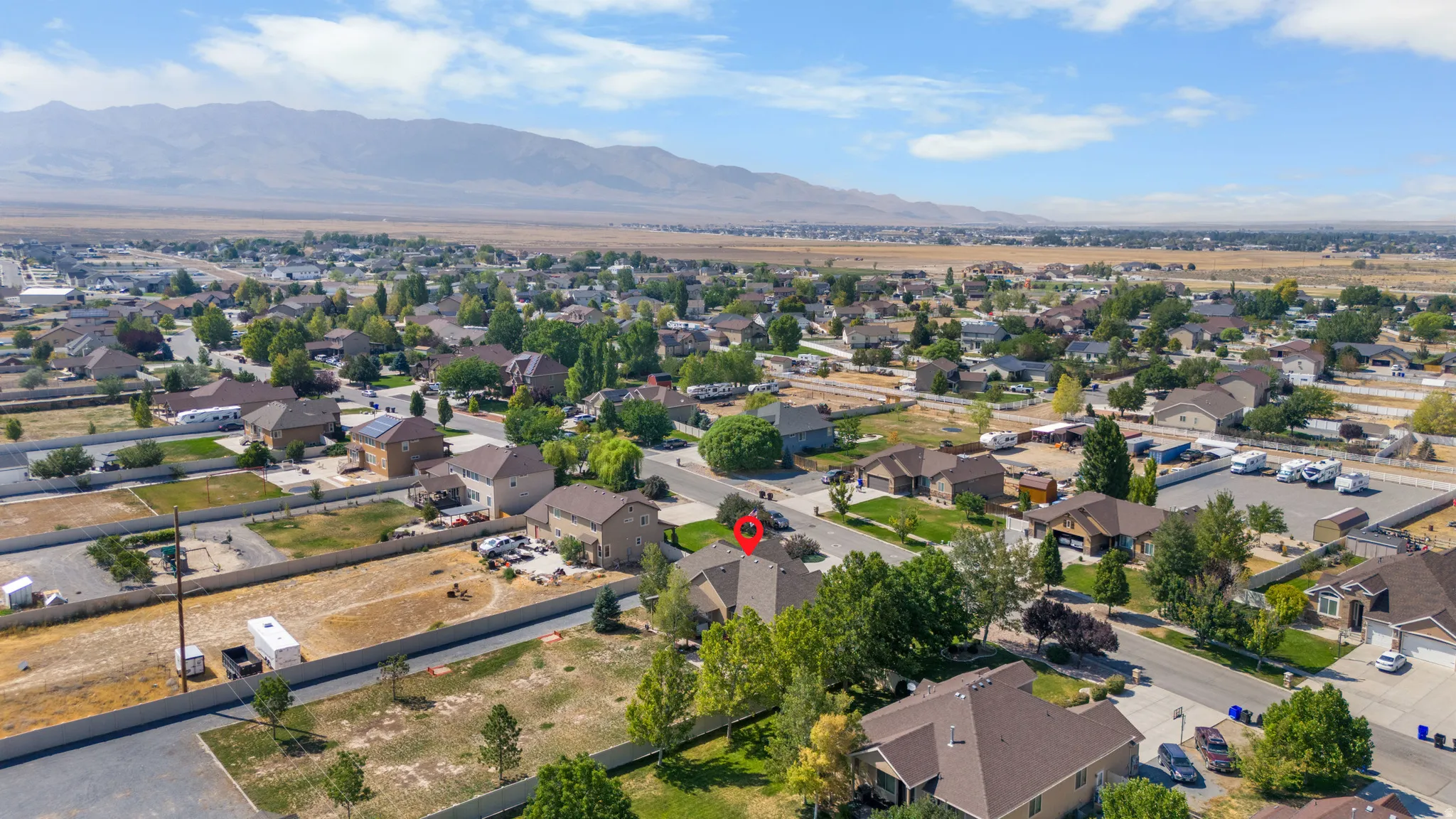 Residential neighborhood with established homes, mature trees, and mountainous terrain in the background