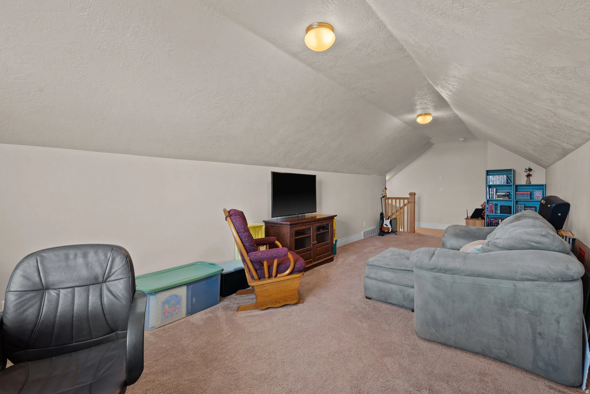 Carpeted room with sloped ceilings and recessed lighting