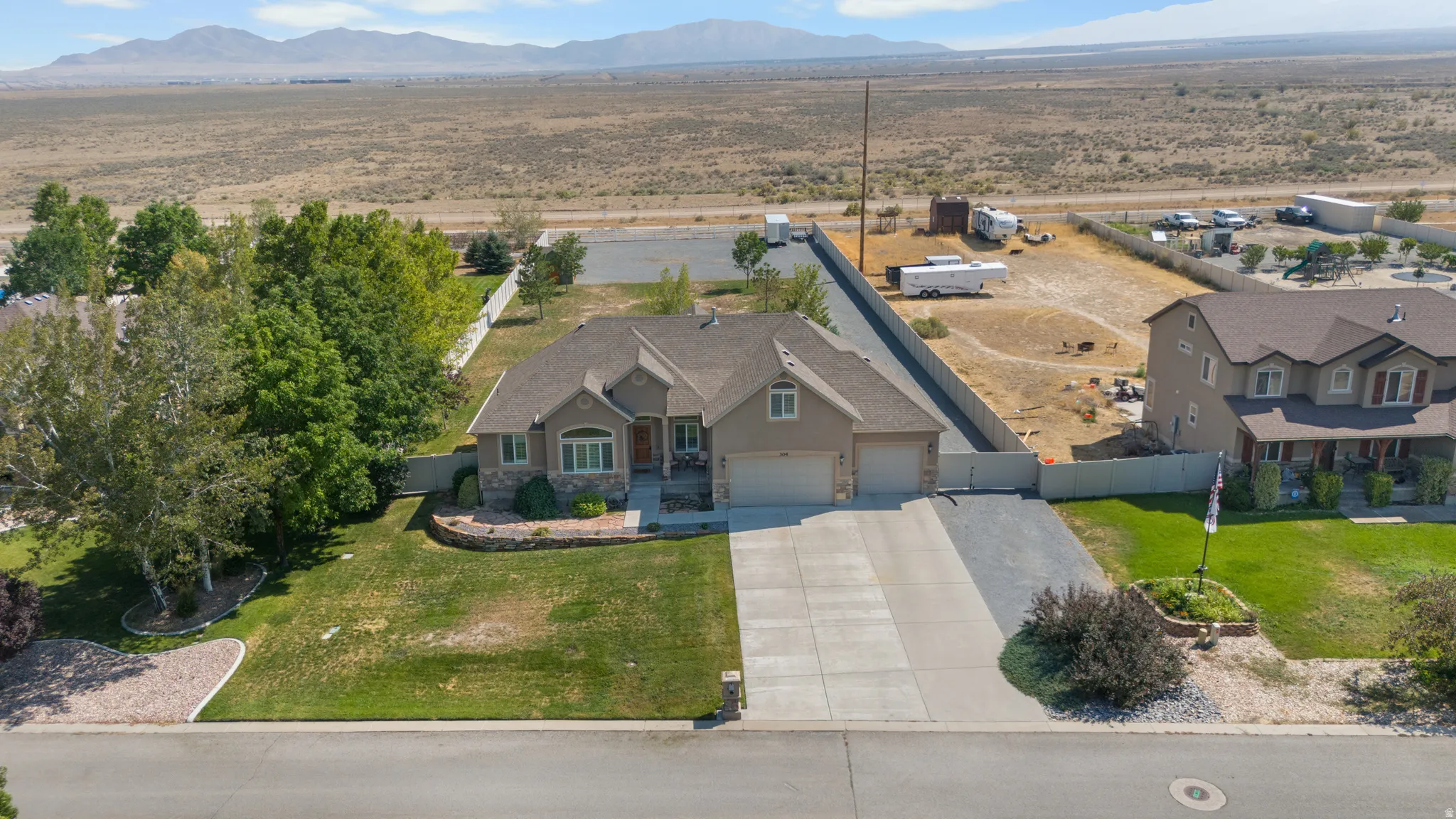 Stone facade residence with an attached two-car garage, concrete driveway, and front lawn