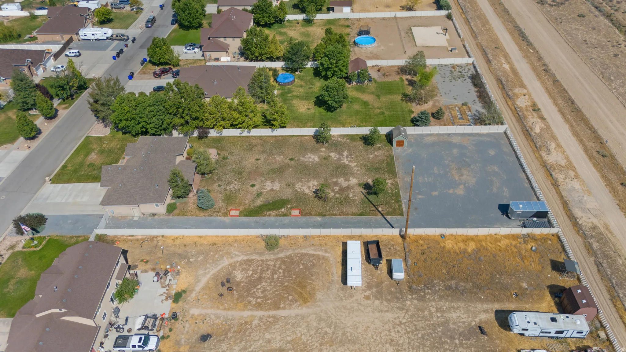 Expansive parcel with a large gravel lot, enclosed by a perimeter fence