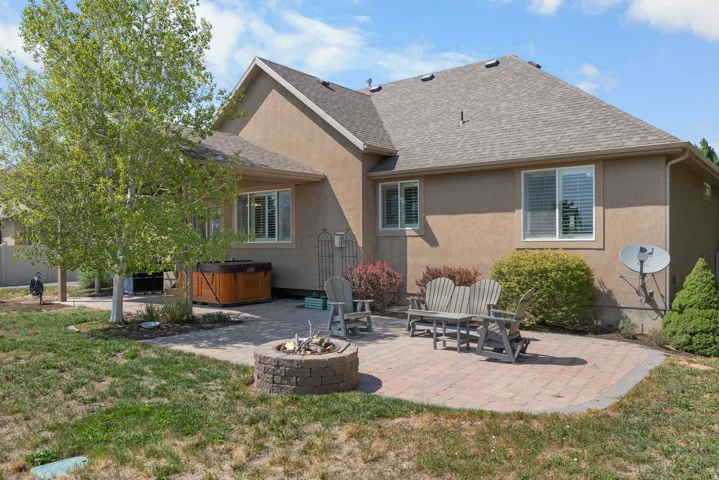 Expansive paver patio featuring a built-in stone fire pit and a wood-finish hot tub