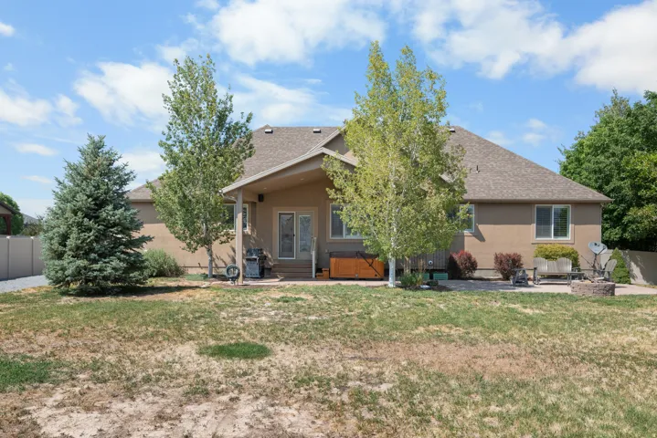 Rear exterior featuring a covered patio, multiple windows, and a paved outdoor area with a fire pit
