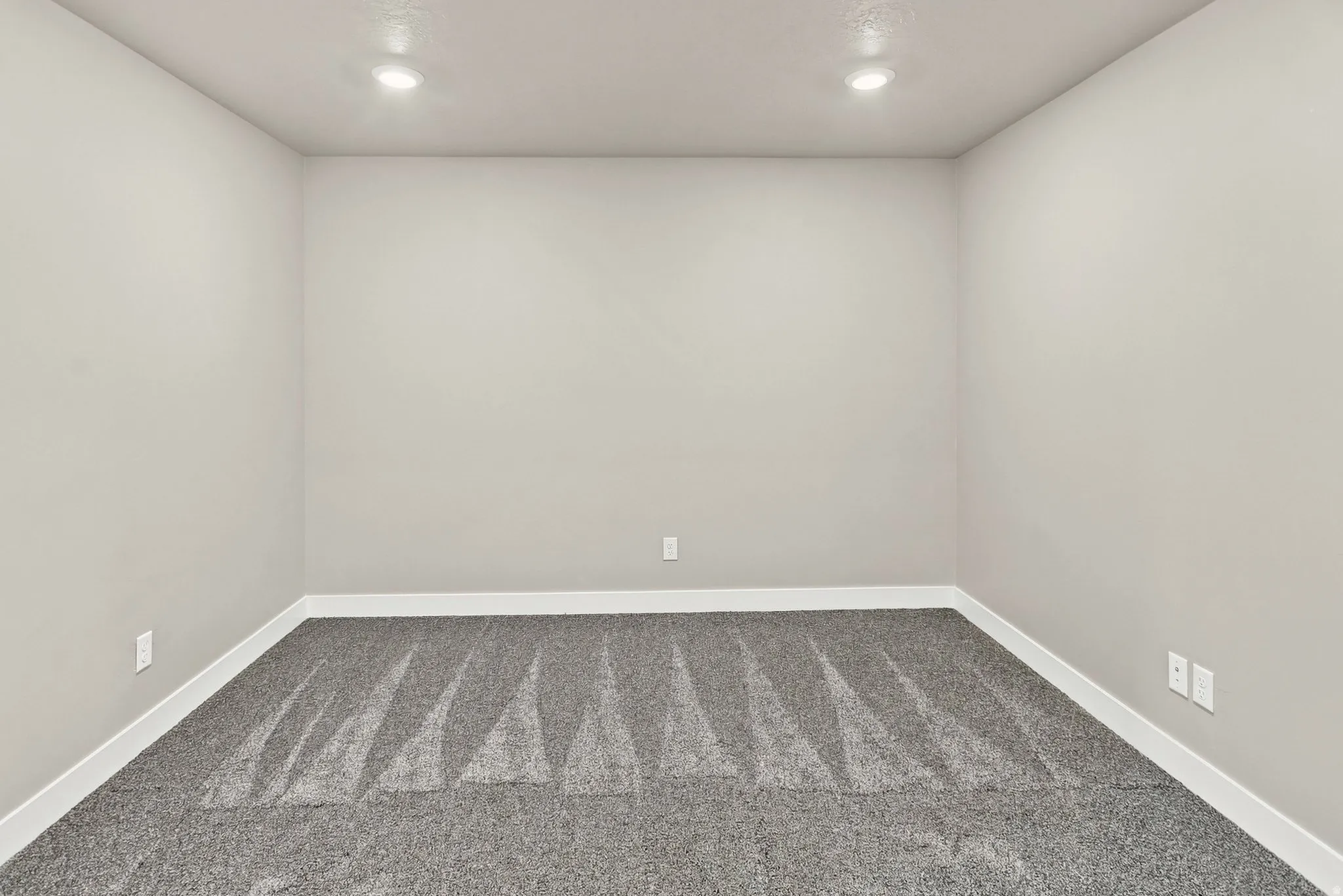 Recessed lighting illuminates the neutral wall tones and patterned carpeting