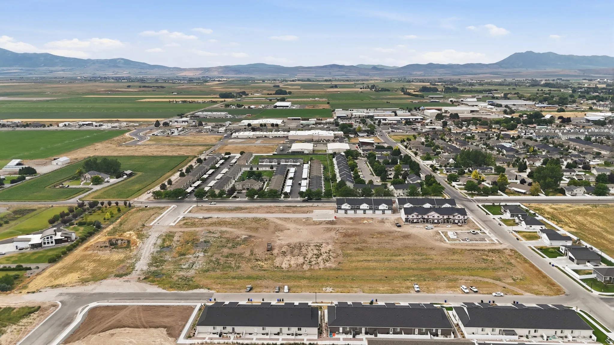 Expansive development site featuring partially constructed residential buildings, paved roadways, and undeveloped land parcels