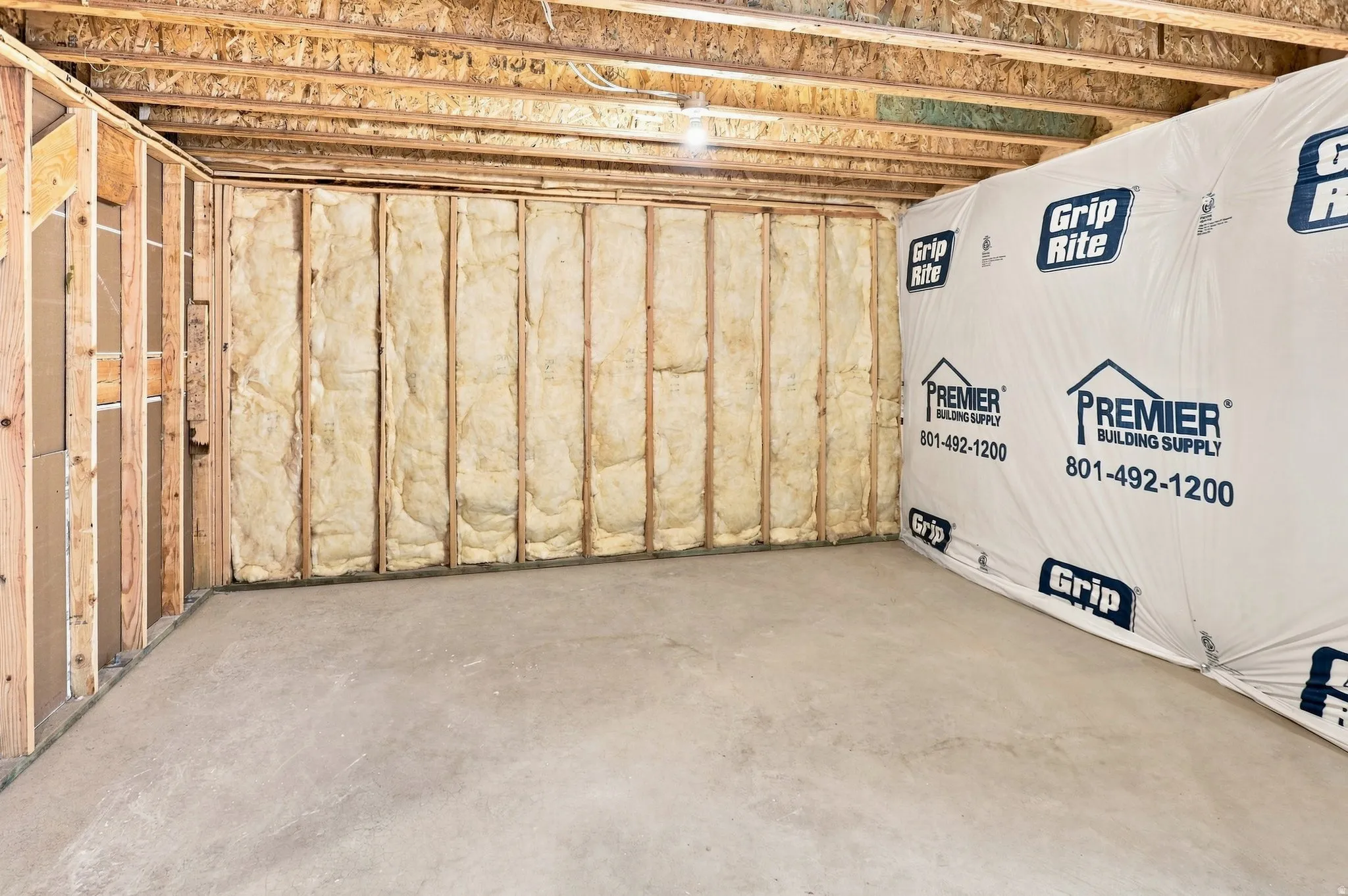 Unfinished basement featuring exposed wood framing, ceiling joists, and concrete flooring