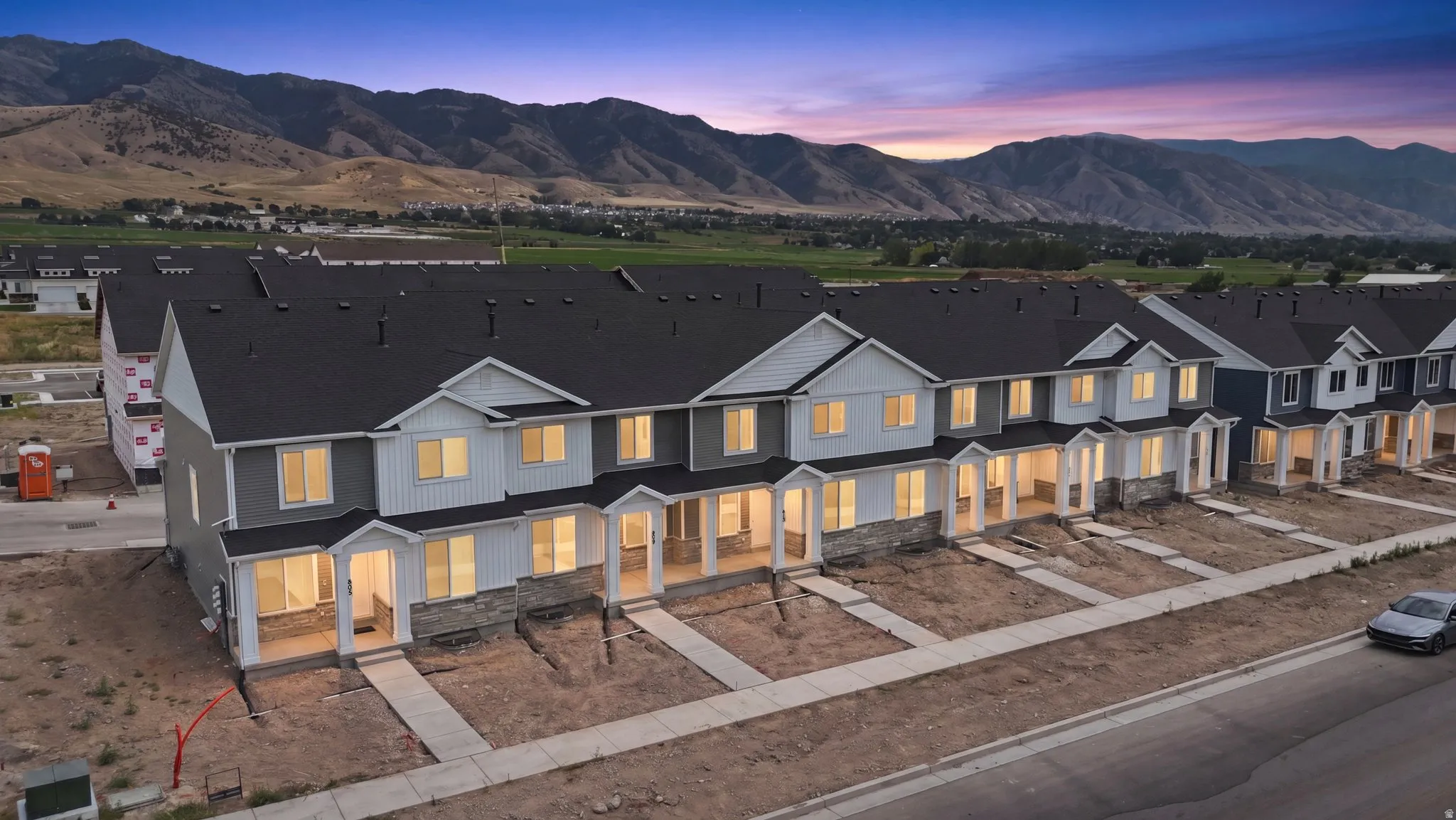 Row of townhomes featuring varied exterior finishes, covered front porches, and individual sidewalks