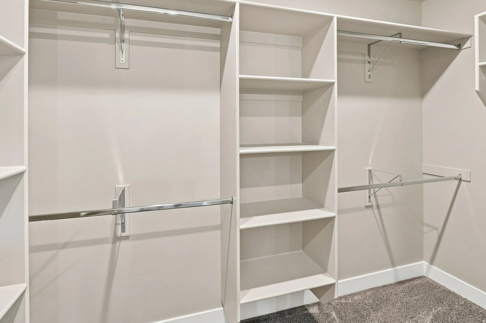 Built-in closet organization system featuring multiple shelving units, hanging rods, and a neutral color palette
