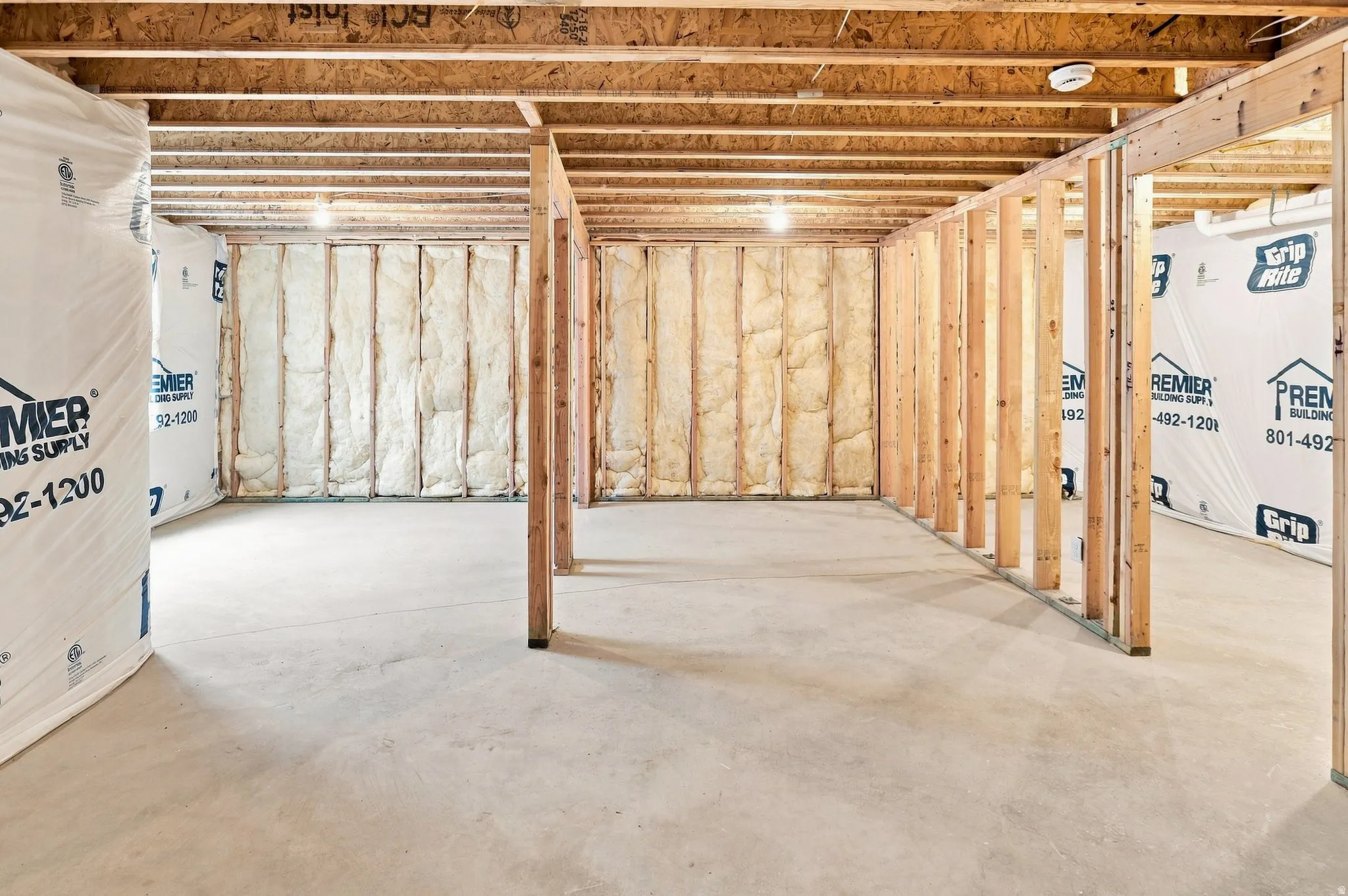 Unfinished basement with exposed wood framing, concrete flooring, and ceiling joists