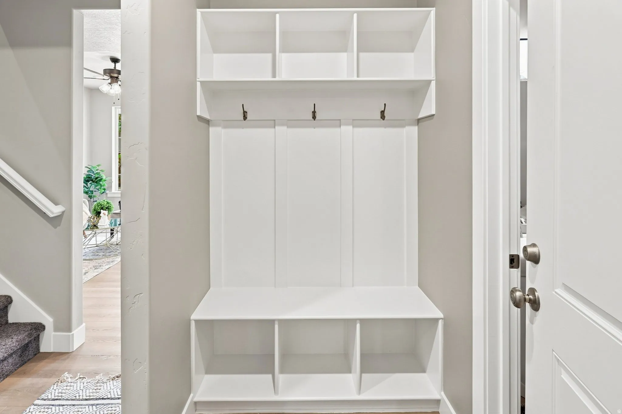 Built-in storage bench with three open compartments and upper shelving