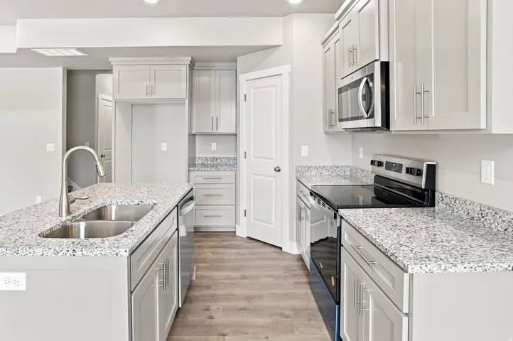 Kitchen featuring light grey cabinetry, stone-finish countertops, stainless steel appliances, and wood-finish flooring