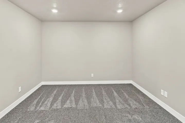 Recessed lighting illuminates the neutral wall tones and patterned carpeting