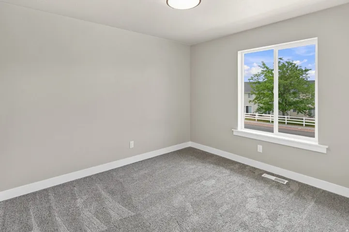 Light gray walls with white trim, gray carpet flooring, and a large window