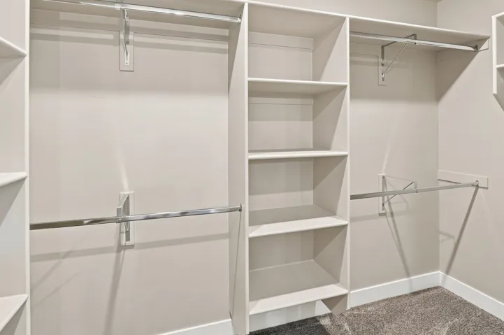 Built-in closet organization system featuring multiple shelving units, hanging rods, and a neutral color palette