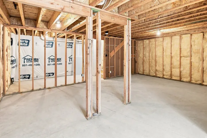 Unfinished basement with concrete flooring, exposed wood framing, and ceiling joists