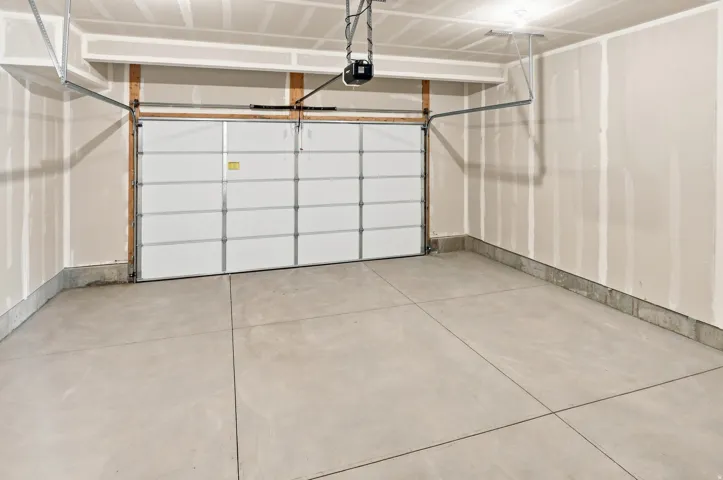 Expansive garage space featuring a concrete floor, automatic garage door opener, and unfinished drywall walls