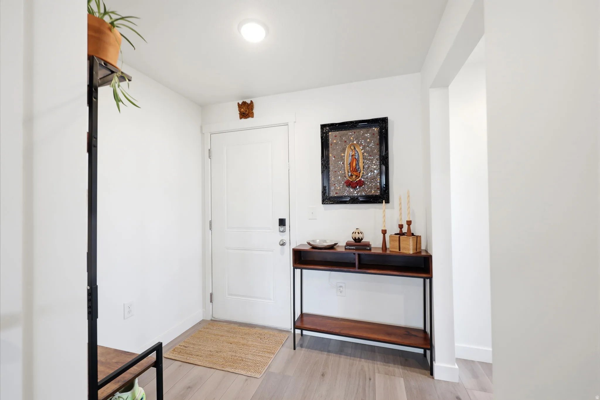 Light-toned wood-finish flooring, recessed ceiling lighting, and a solid white entry door