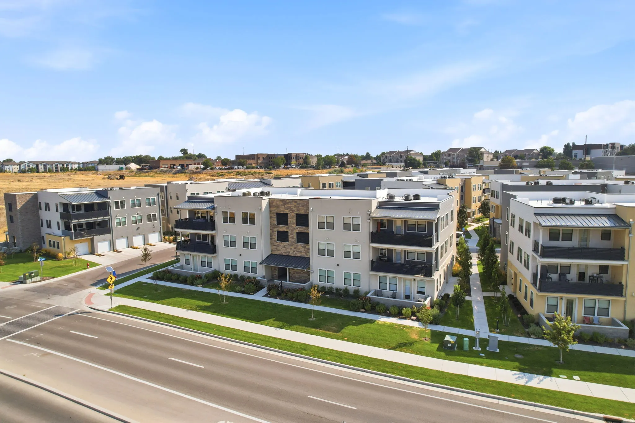 Contemporary multi-story buildings featuring balconies, attached garages, and a landscaped courtyard